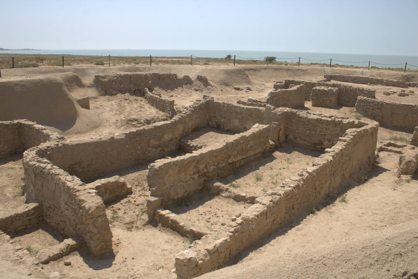 Ancient ruins with stone structures on a sandy landscape under a clear sky.